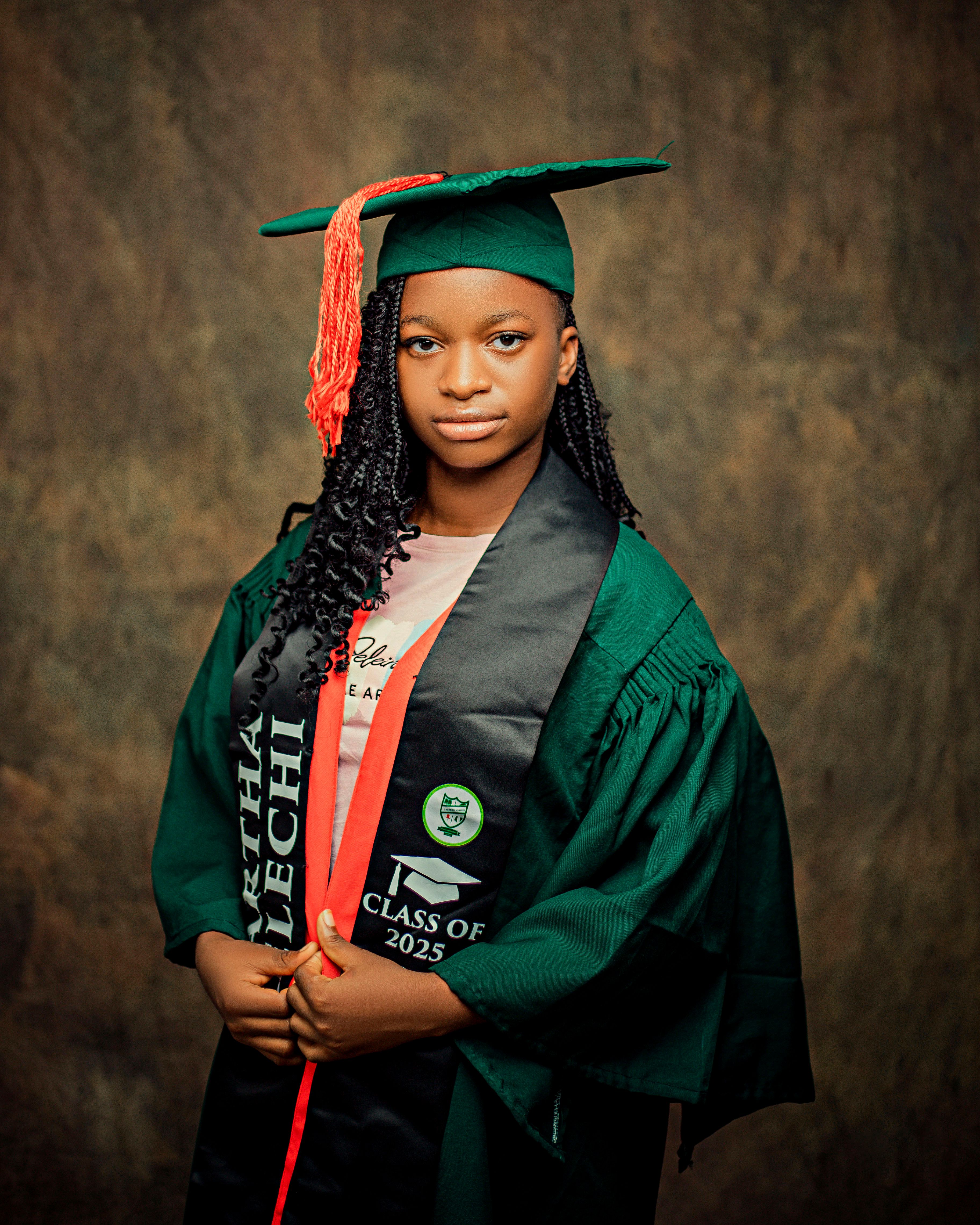 Portrait of a young graduate wearing green cap and gown with a Class of 2025 sash.