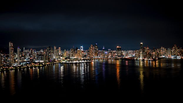 Night view of Panama City's skyline with reflections in the ocean.