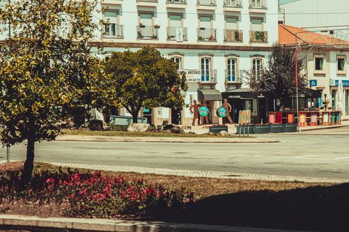 Free A sunny town square with colorful chairs and lush trees, perfect for a summer stroll. Stock Photo