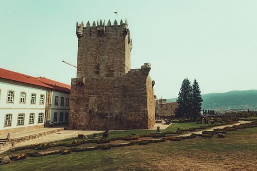 A scenic view of a historic stone tower surrounded by gardens and mountains.