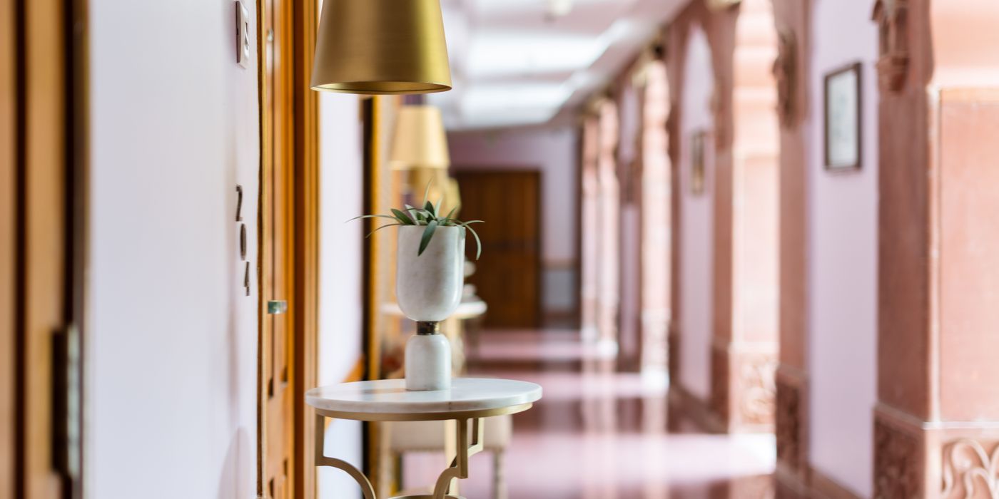 Long hotel corridor lined with guest room doors and patterned carpet