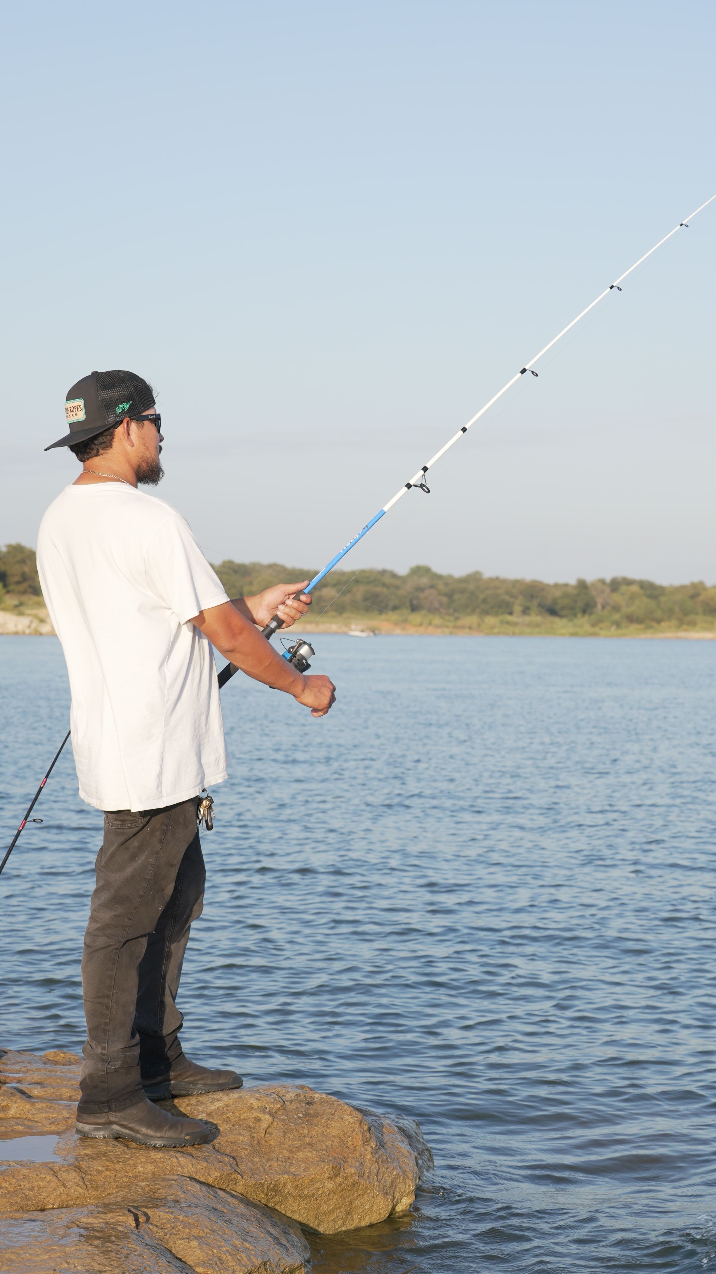 An adult man fishing on a lakeside in Flower Mound, Texas, enjoying a peaceful moment outdoors.