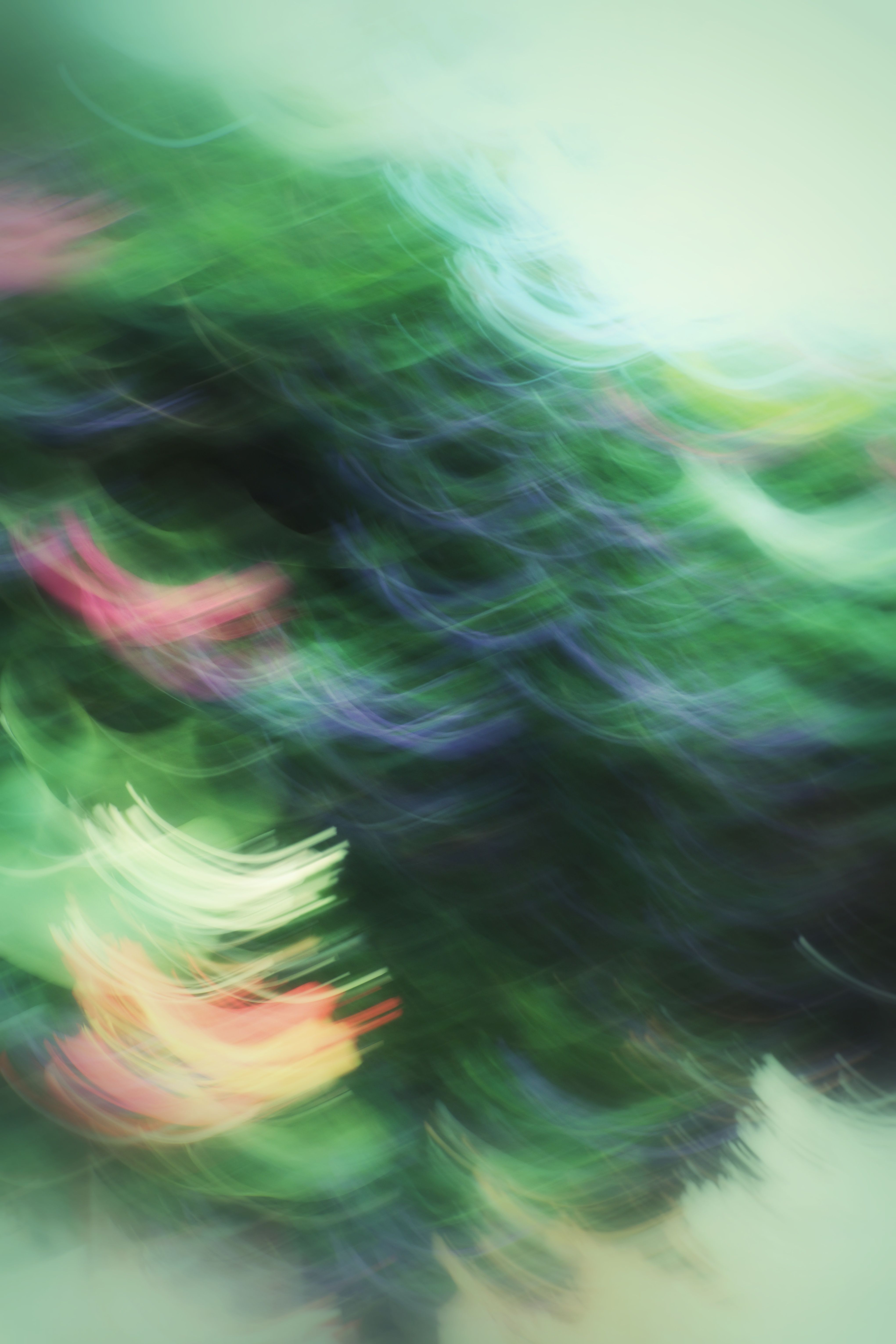 A vibrant abstract art photo showcasing swirling motion blur in green, pink, and blue hues.