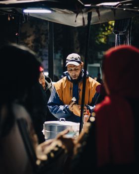 Busy Moroccan night market with a street vendor serving customers under warm lights.