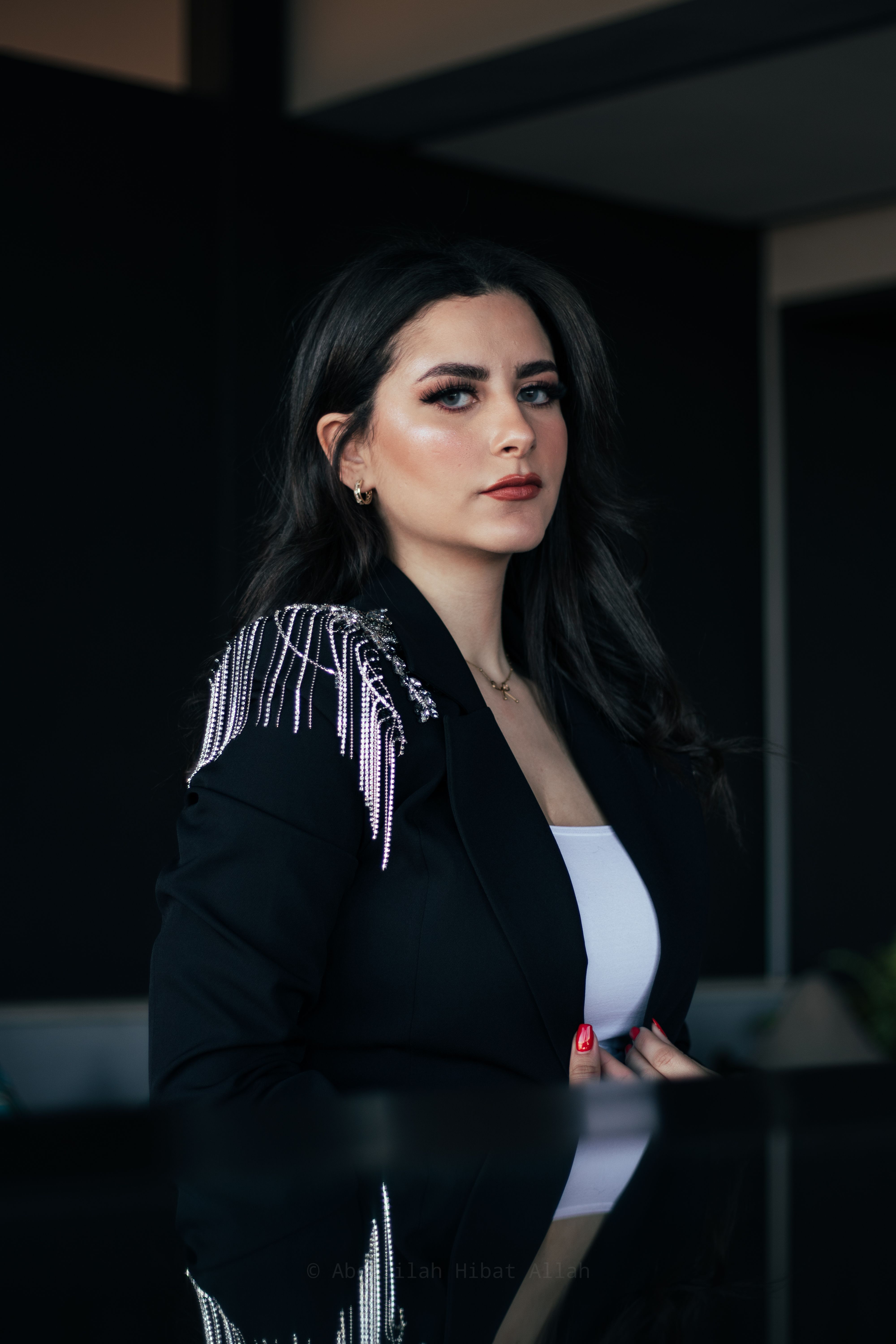 Portrait of a confident woman in a stylish black jacket with chain detail, looking poised and elegant.