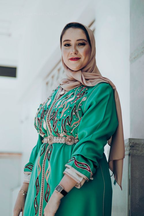 Free Portrait of a smiling woman in a stylish hijab and dress with intricate design. Stock Photo