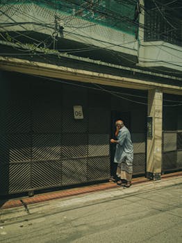 Man standing outside a building in a street of Dhaka on a sunny day.