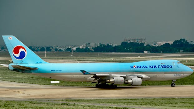 A Korean Air Cargo Boeing 747 taxies on a runway with a city skyline in the background.