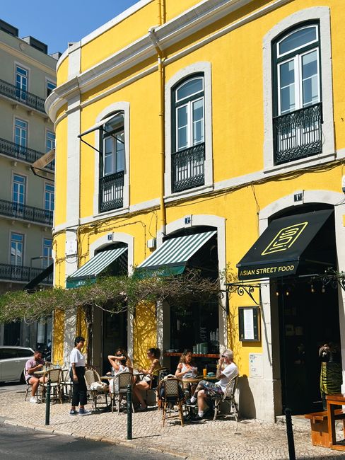 Yellow building with outdoor dining at an Asian street food cafe in Lisbon.