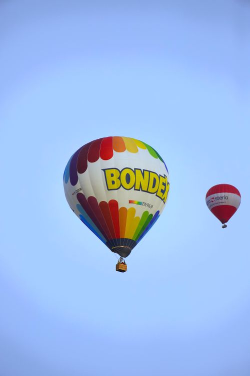 Free Colorful hot air balloons soar against a bright blue sky, showcasing vibrant patterns and designs. Stock Photo