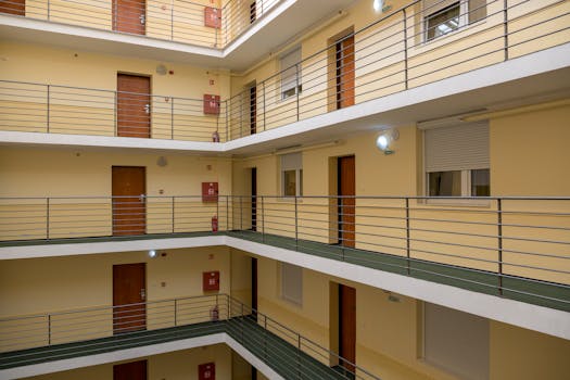 Interior view of a multi-story apartment building with metal railings and wooden doors.