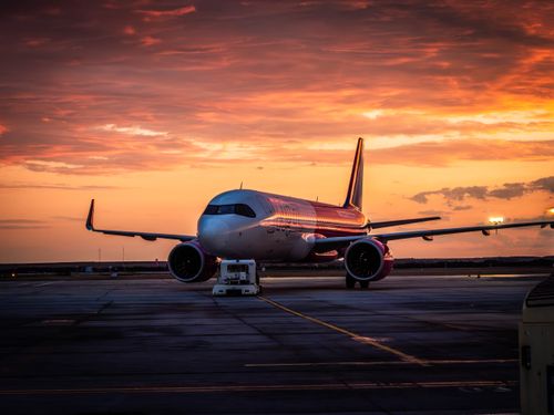 Free A commercial airplane stationed at Timișoara Airport with a stunning sunrise backdrop. Stock Photo