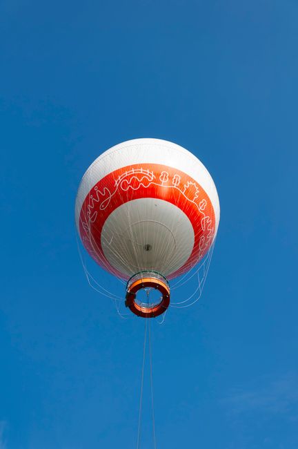 A vibrant red and white hot air balloon soars against a clear blue sky, offering a sense of adventure and freedom.