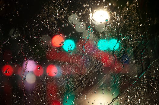 Raindrops on a window with vibrant city lights in the background at night.