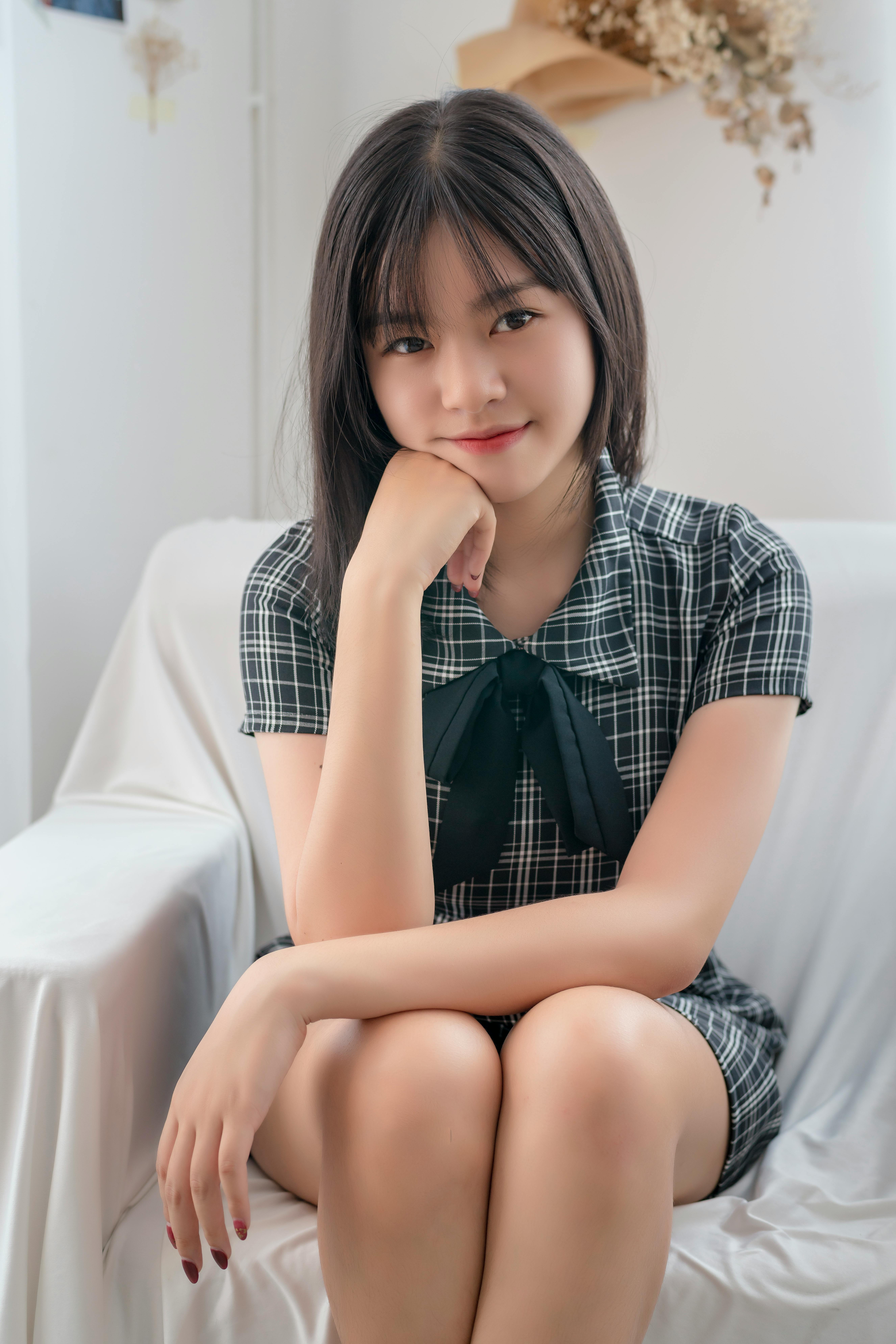 Young woman sitting comfortably on a chair indoors, smiling gently.