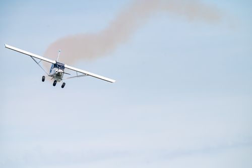 Free A stunt plane executes maneuvers with a trailing smoke in a clear blue sky. Stock Photo