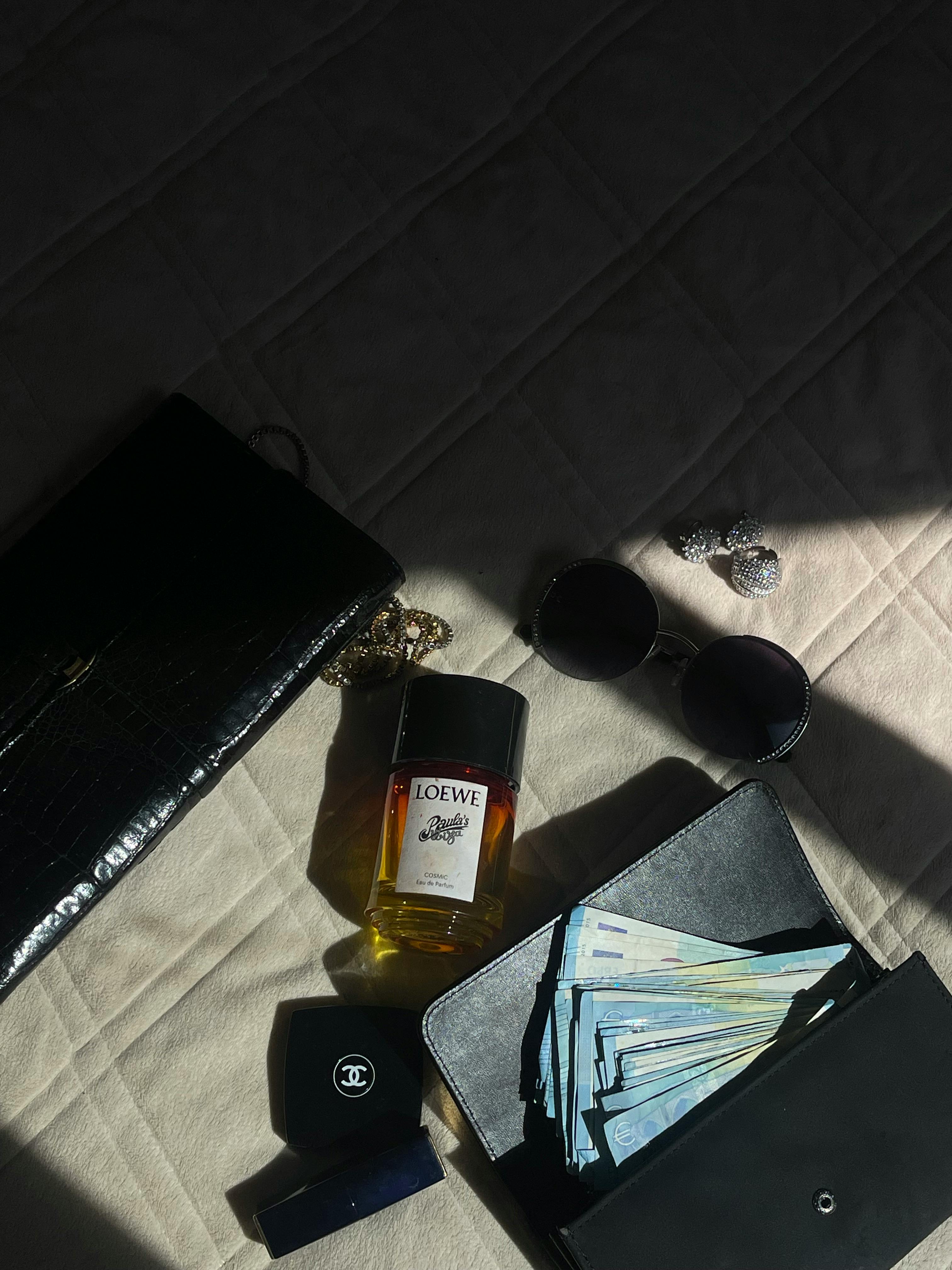 Gratis Elegante composizione che espone profumi, occhiali da sole, gioielli e valute, perfetta per temi legati alla moda e al lusso. Foto a disposizione