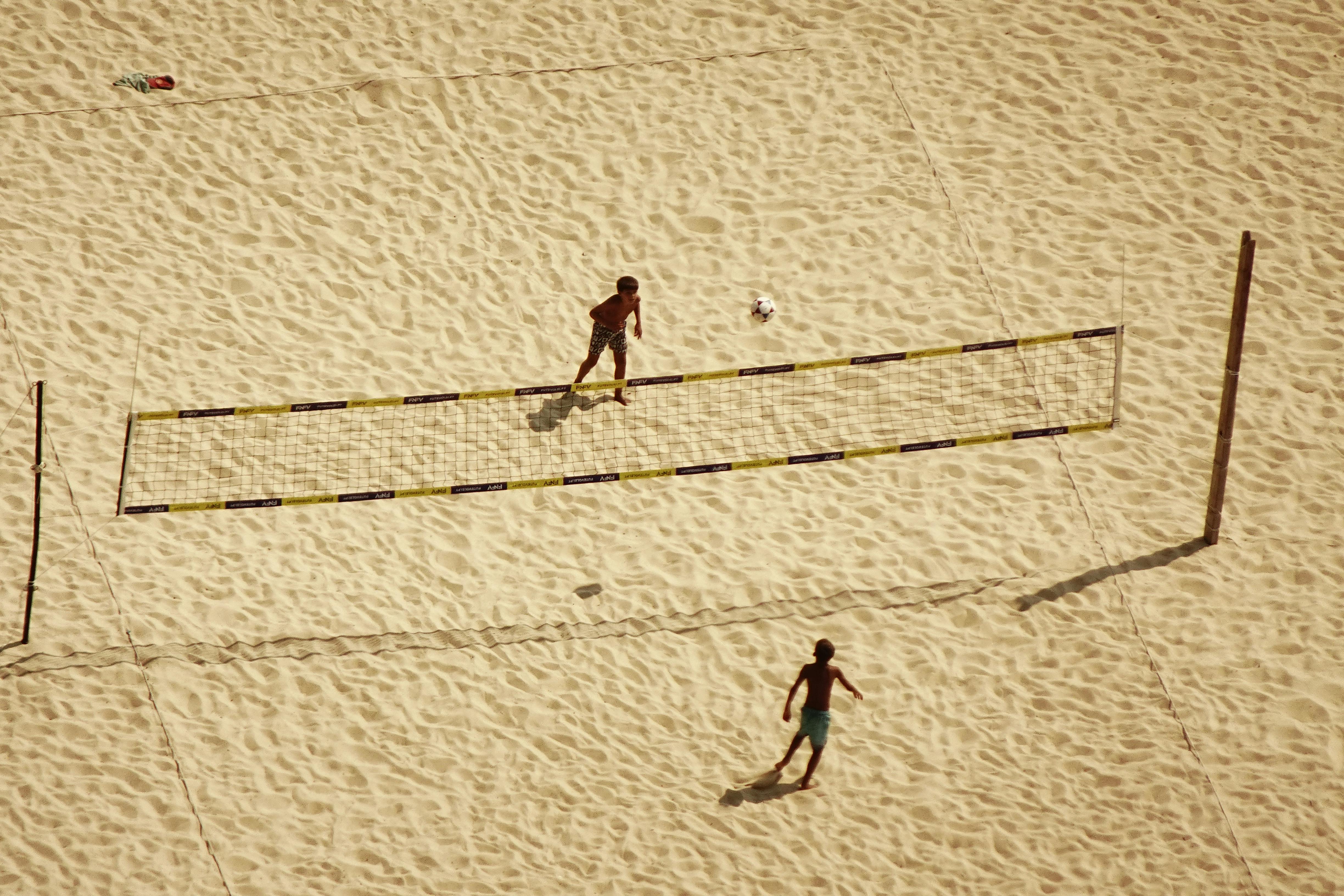 De franc Dues persones juguen a voleibol en una platja de sorra, vistes des de dalt. Foto d'estoc