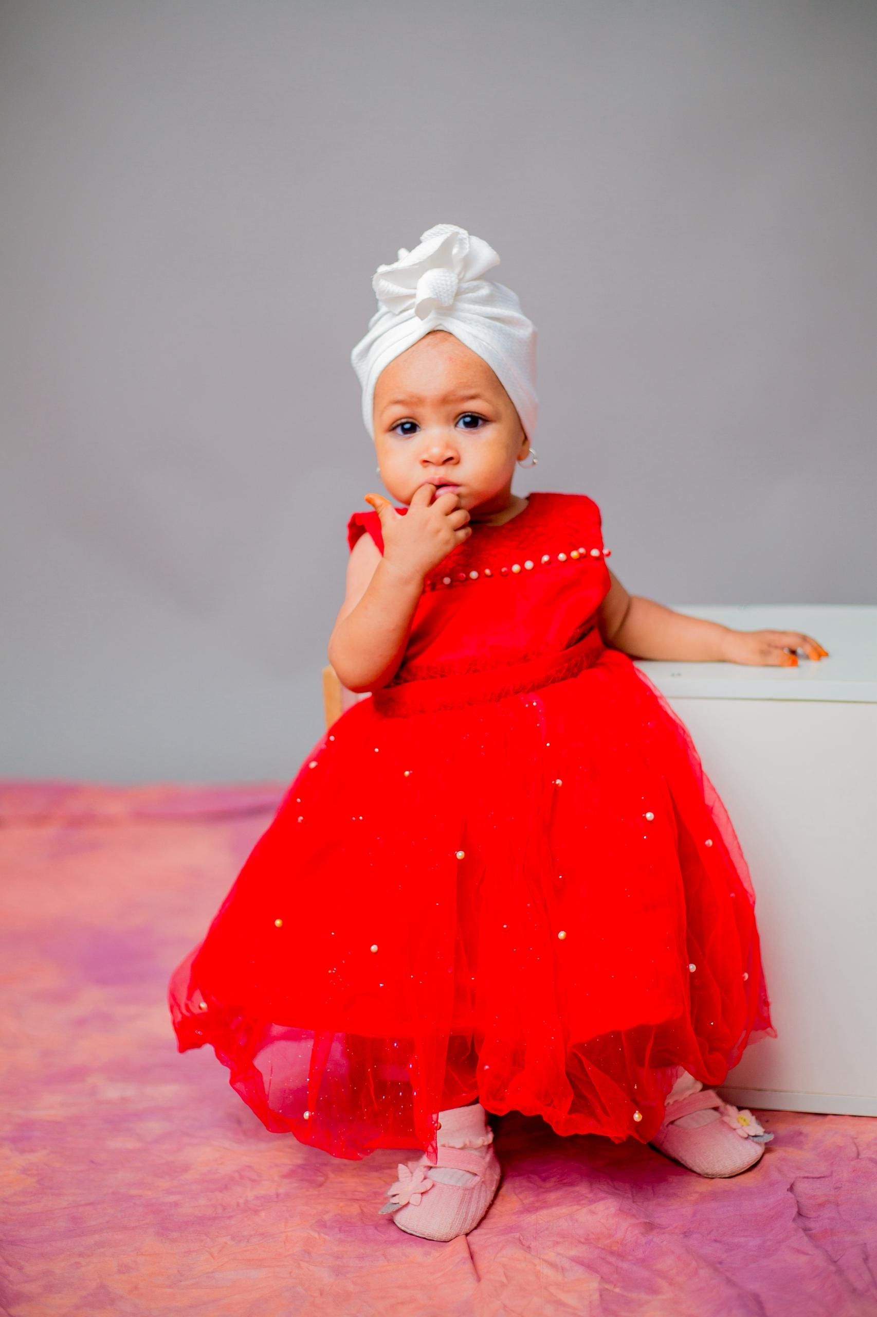 Adorable Baby in Red Dress with White Headwrap  Free Stock Photo