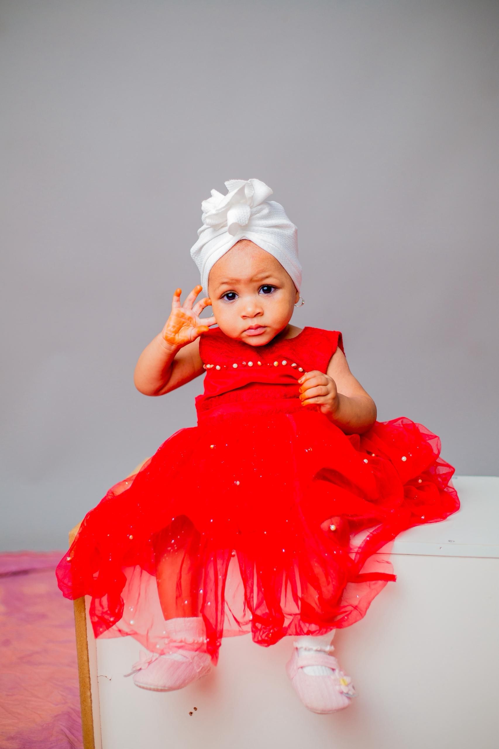 Adorable Baby in Red Dress with White Headwrap  Free Stock Photo
