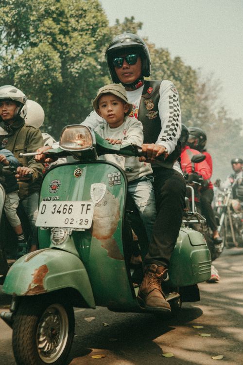 Free Father and son on a classic scooter at a Bandung street parade. Stock Photo