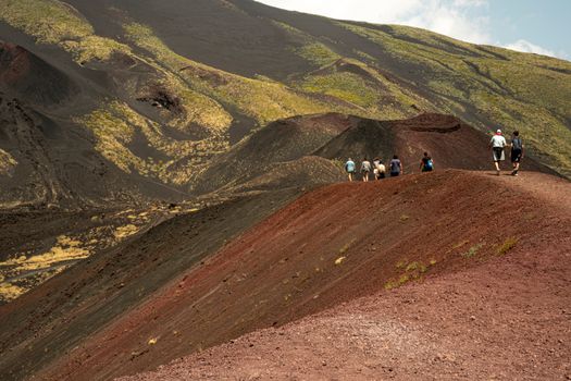 Group trekking on Mount Etna's volcanic landscape in Sicily, Italy.