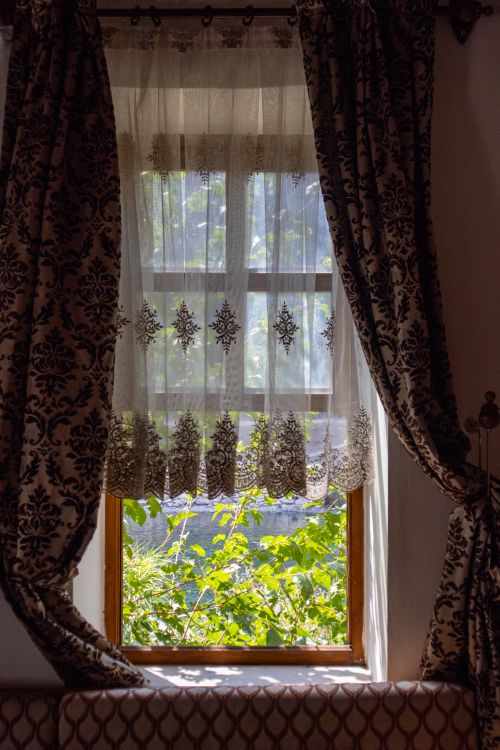 Free A beautifully adorned window in Palu, Türkiye with sunlight filtering through sheer, patterned curtains. Stock Photo