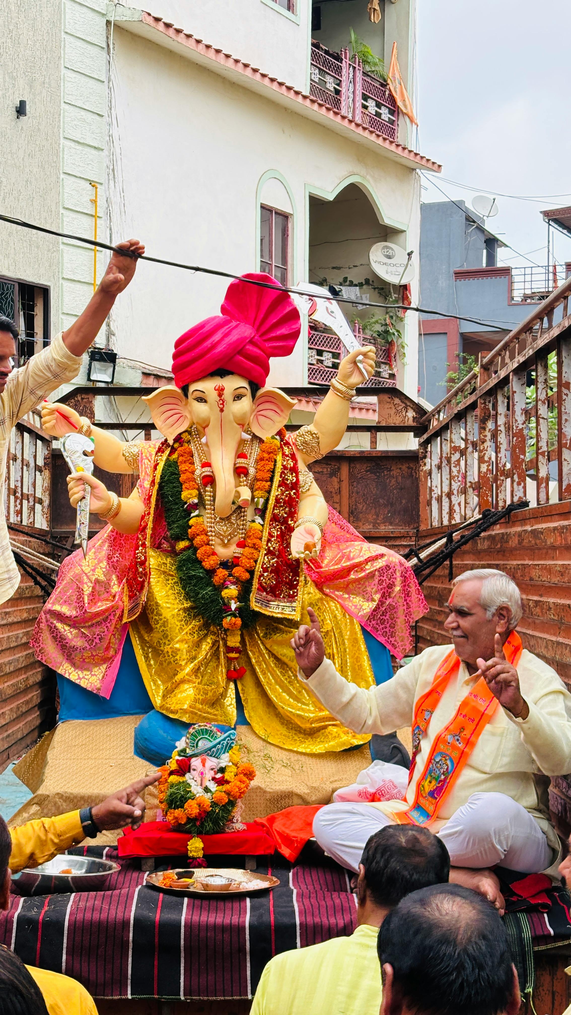 Colorful celebration of Ganesh Chaturthi featuring a detailed idol and joyous devotees outdoors.
