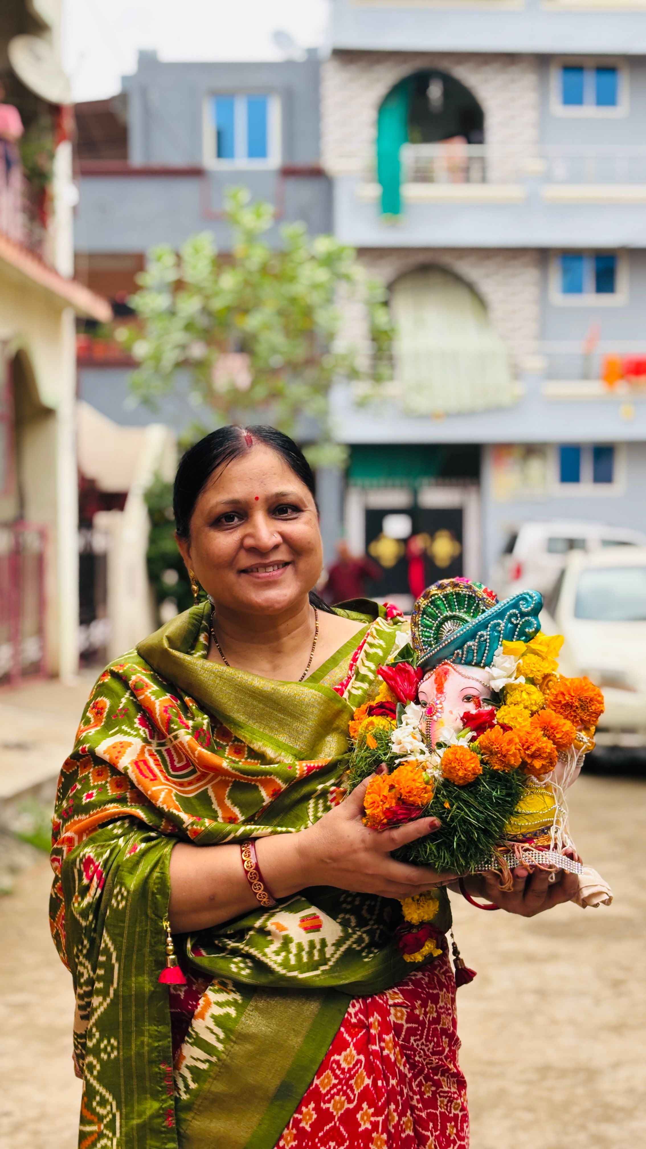 Smiling woman holding colorful bouquet on a vibrant urban street.