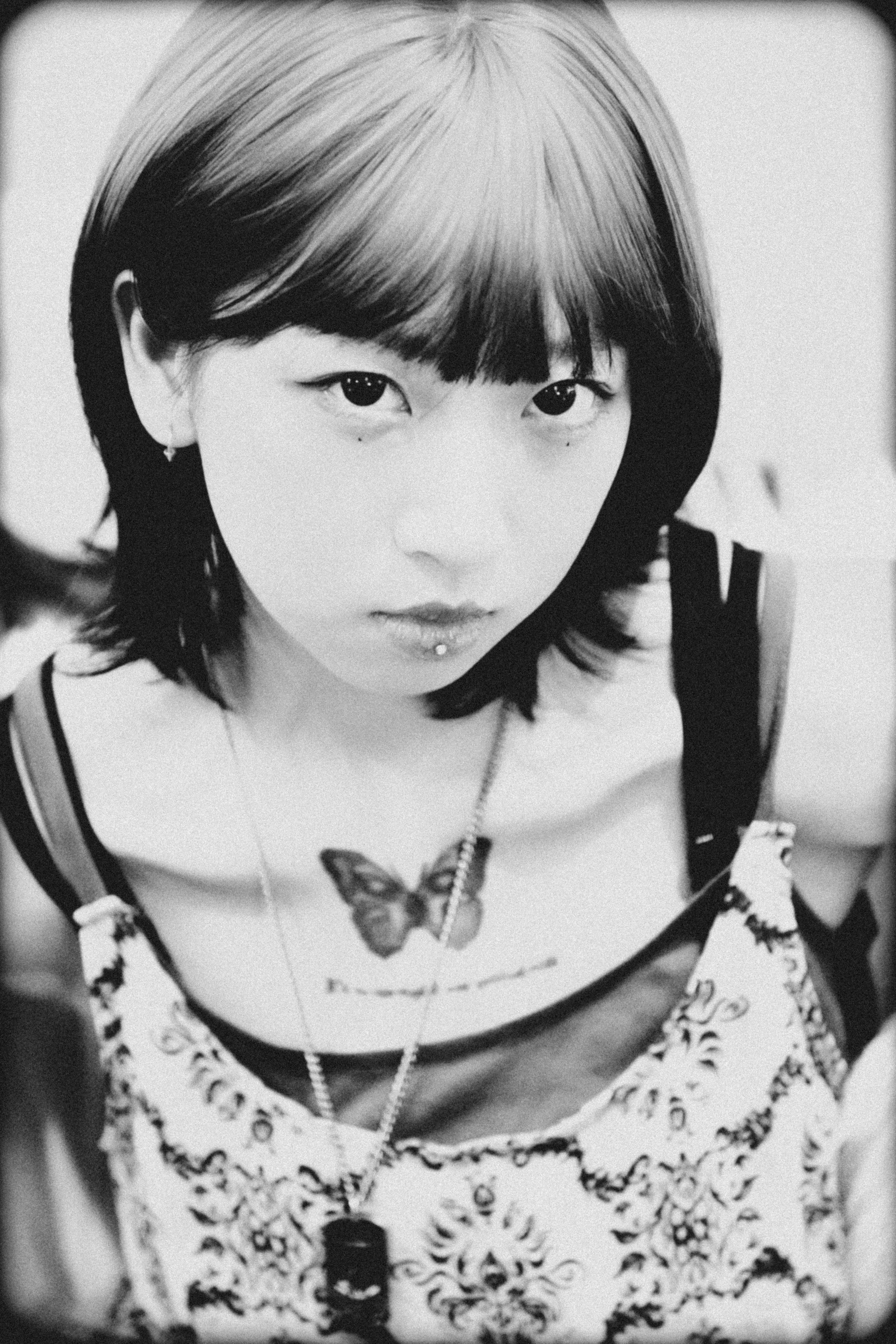 ingyenes Stílusos fekete-fehér portré egy fiatal nőről, pillangó tetoválással a mellkasán. Stockfotó