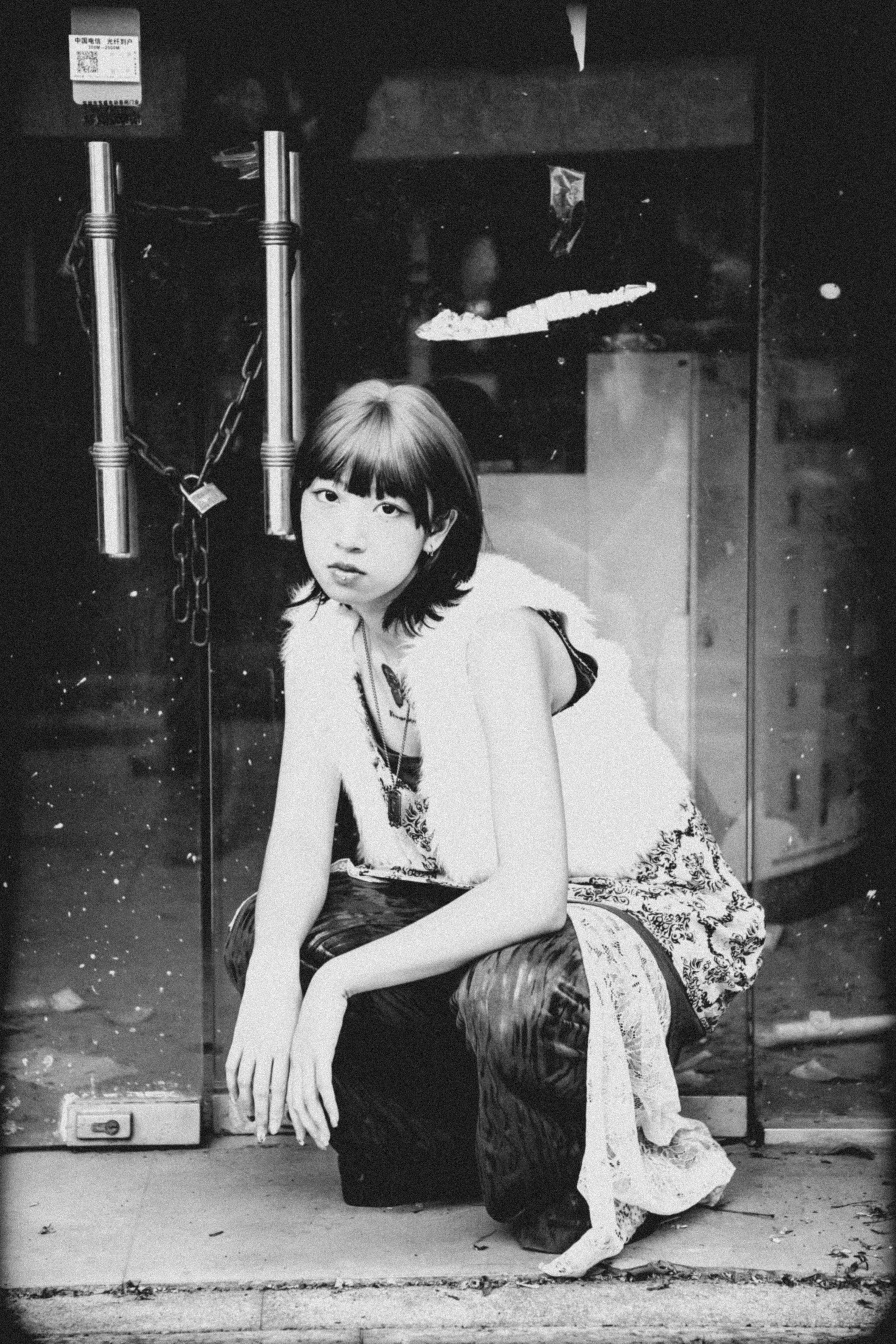 Free Artistic black and white portrait of a young woman seated outdoors. Stock Photo