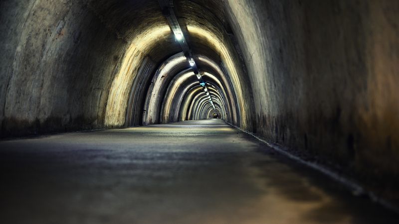 Mysterious underground tunnel with arched lights creating a moody atmosphere.