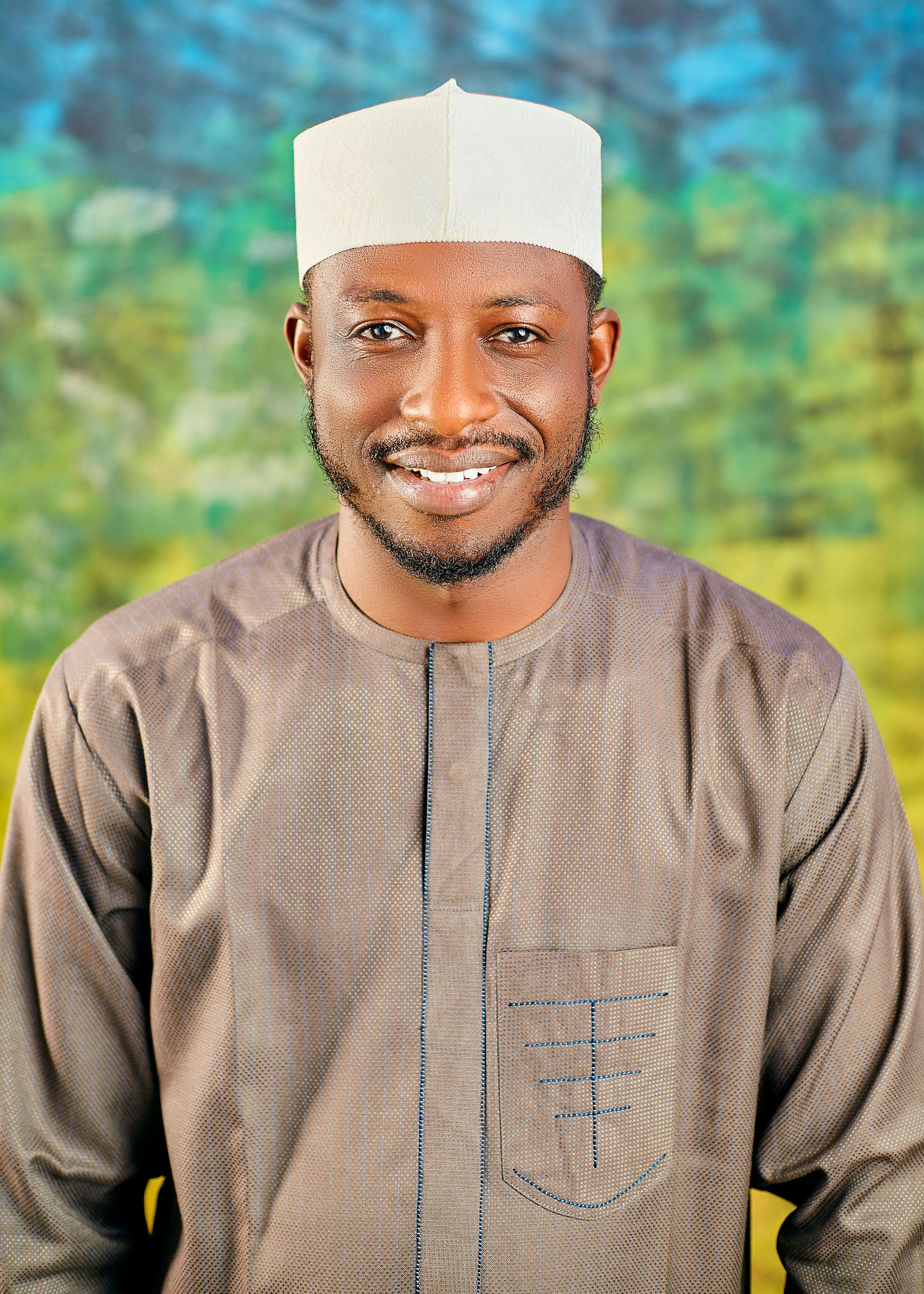 A cheerful man wearing traditional attire, posing against a colorful backdrop.