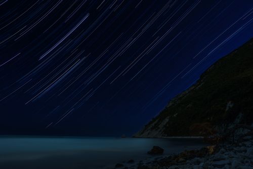Free Dazzling star trails illuminating the sky over Portonovo Beach, capturing the serene beauty of a summer night. Stock Photo