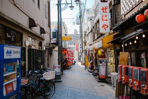 Free Explore a vibrant Japanese alley with colorful signs, vending machines, and bicycles. Stock Photo