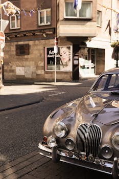 Vintage Jaguar parked on a charming village street, showcasing classic European architecture.