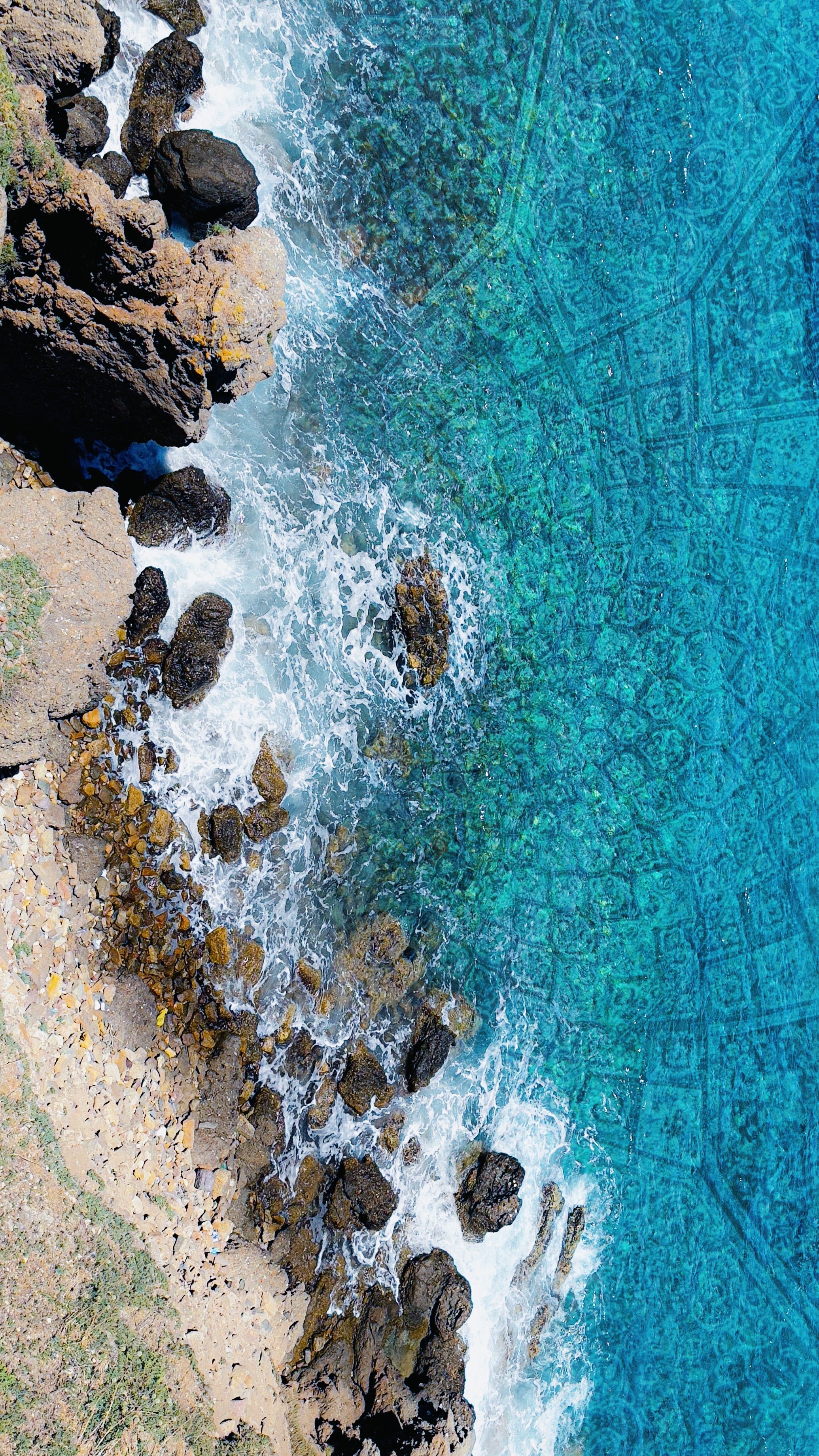 Aerial View of Rocky Shoreline Meeting Turquoise Sea · Free Stock Photo