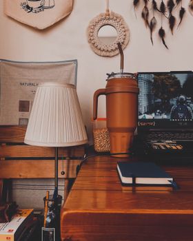 A warm-toned home office featuring a laptop, lamp, and decorative elements. Ideal for lifestyle themes.