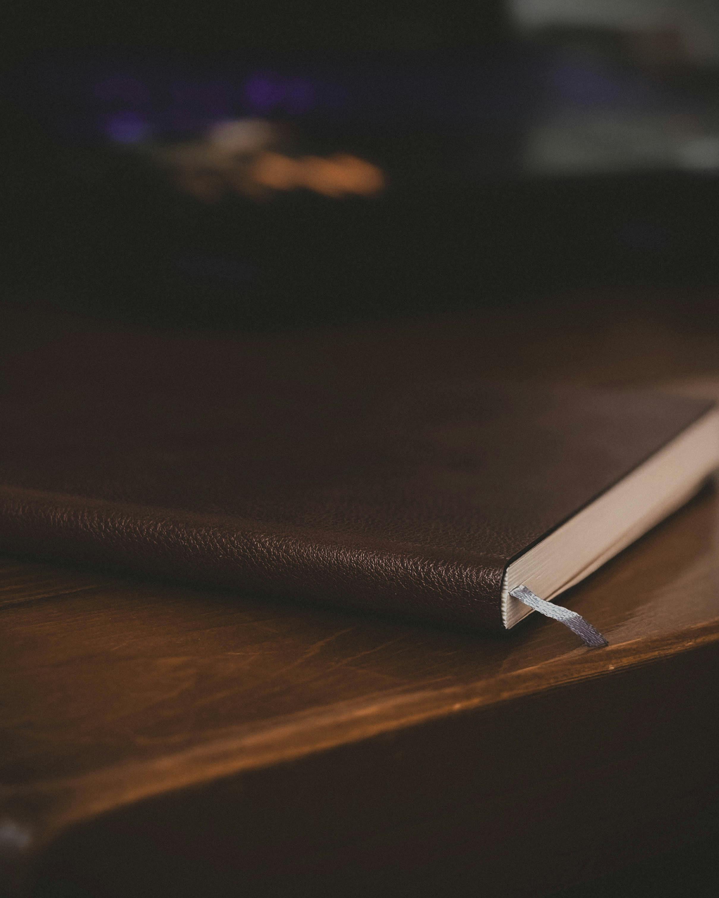 Leather-bound notebook with bookmark lies on a wooden desk, evoking a warm, professional atmosphere.