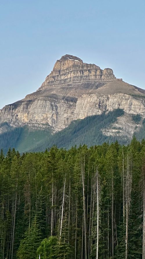 Free Breathtaking view of a tall mountain with a forest in the foreground under a clear sky. Stock Photo
