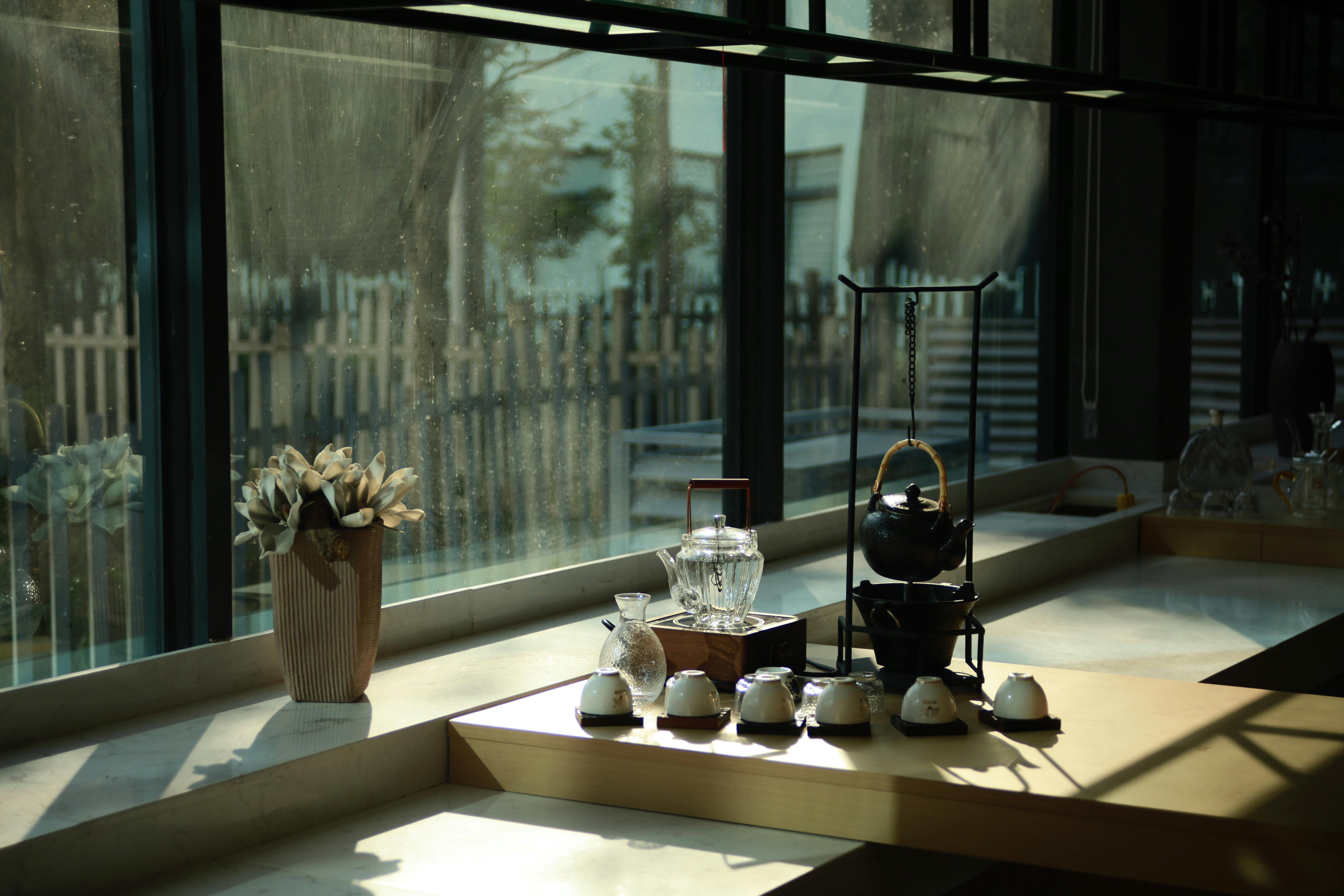 Gratis Un servizio da tè splendidamente apparecchiato e fiori secchi immersi nella calda luce del sole su un ripiano. Foto a disposizione