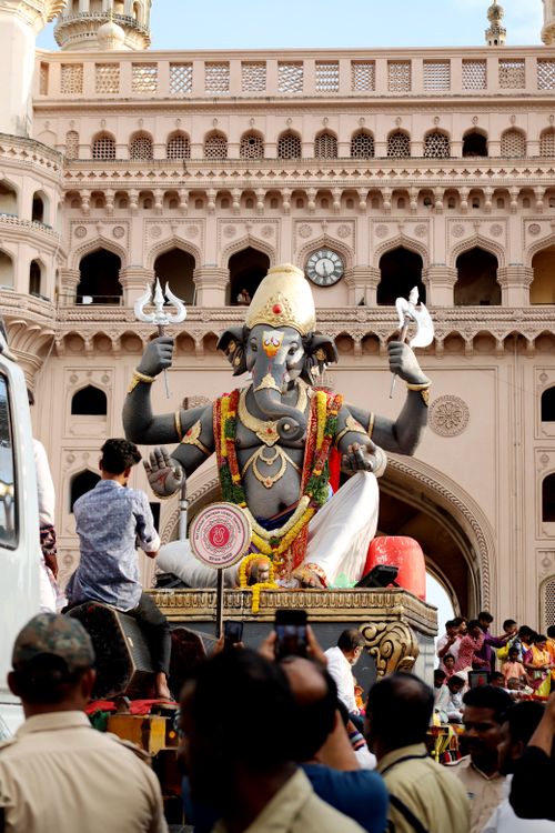 Free People gather around a large Ganesha statue during a festival at a historical arch. Stock Photo