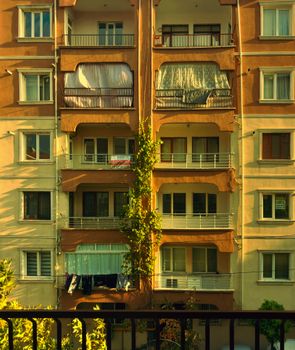 A nostalgic view of an apartment building with balconies in evening sunlight, creating a warm urban atmosphere.