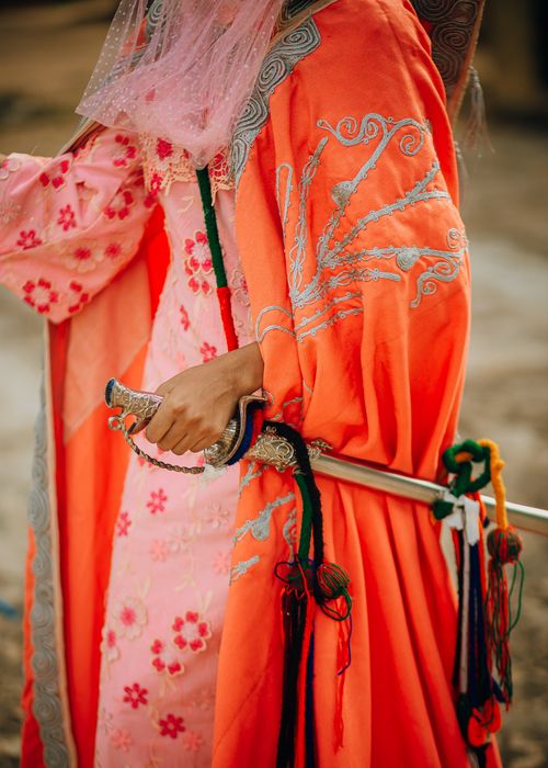 Free A person in vivid traditional attire holds an intricately decorated sword. Stock Photo