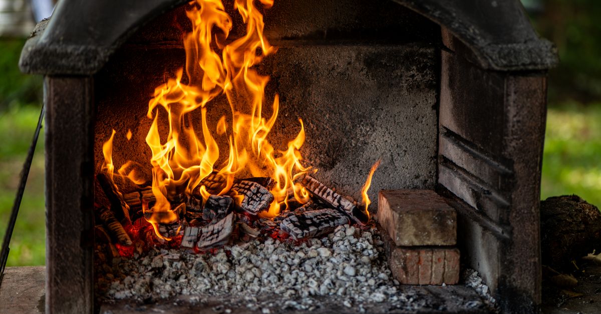 A cozy outdoor fireplace with vibrant flames and burning logs, creating a warm atmosphere.