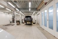 Well-lit garage with a car on a hydraulic lift ready for repair.