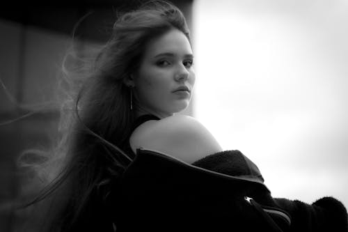 A striking black and white portrait of a young woman outdoors in Ciudad de México, with flowing hair and an intense gaze.