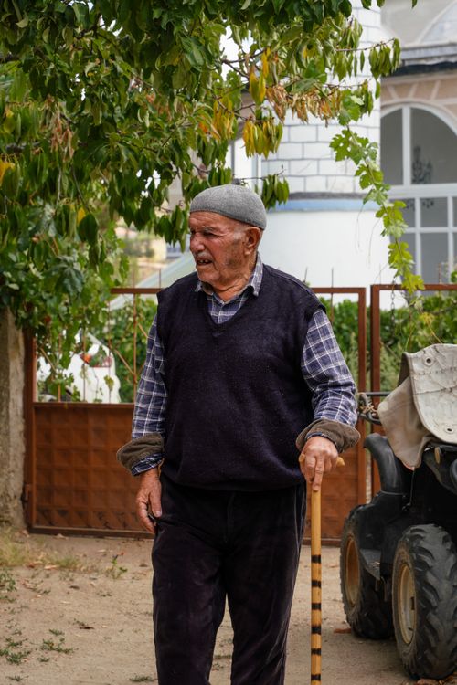 Free An elderly man with a walking stick strolls next to an ATV in a rural outdoor setting. Stock Photo