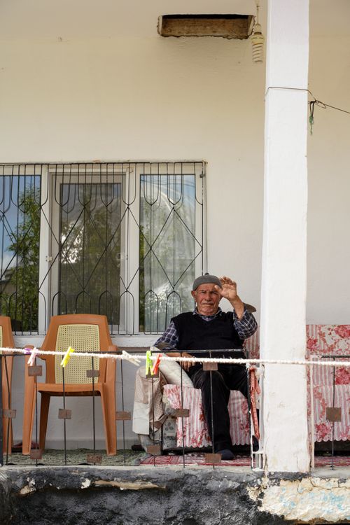 Free Senior man waving from a cozy porch, enjoying sunny day outdoors. Stock Photo