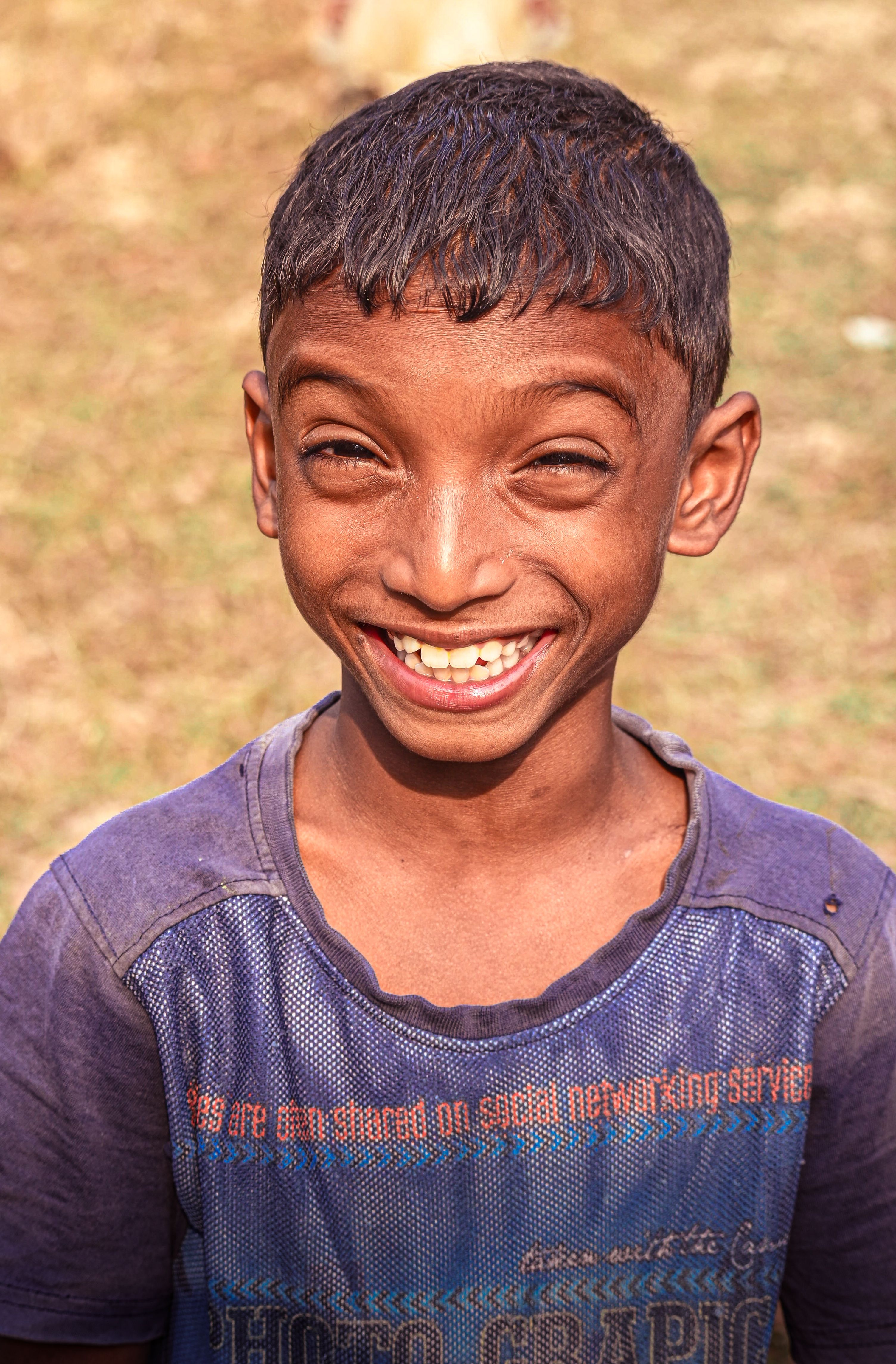 A young boy with a big smile enjoying a sunny day outdoors. His expression is full of joy.